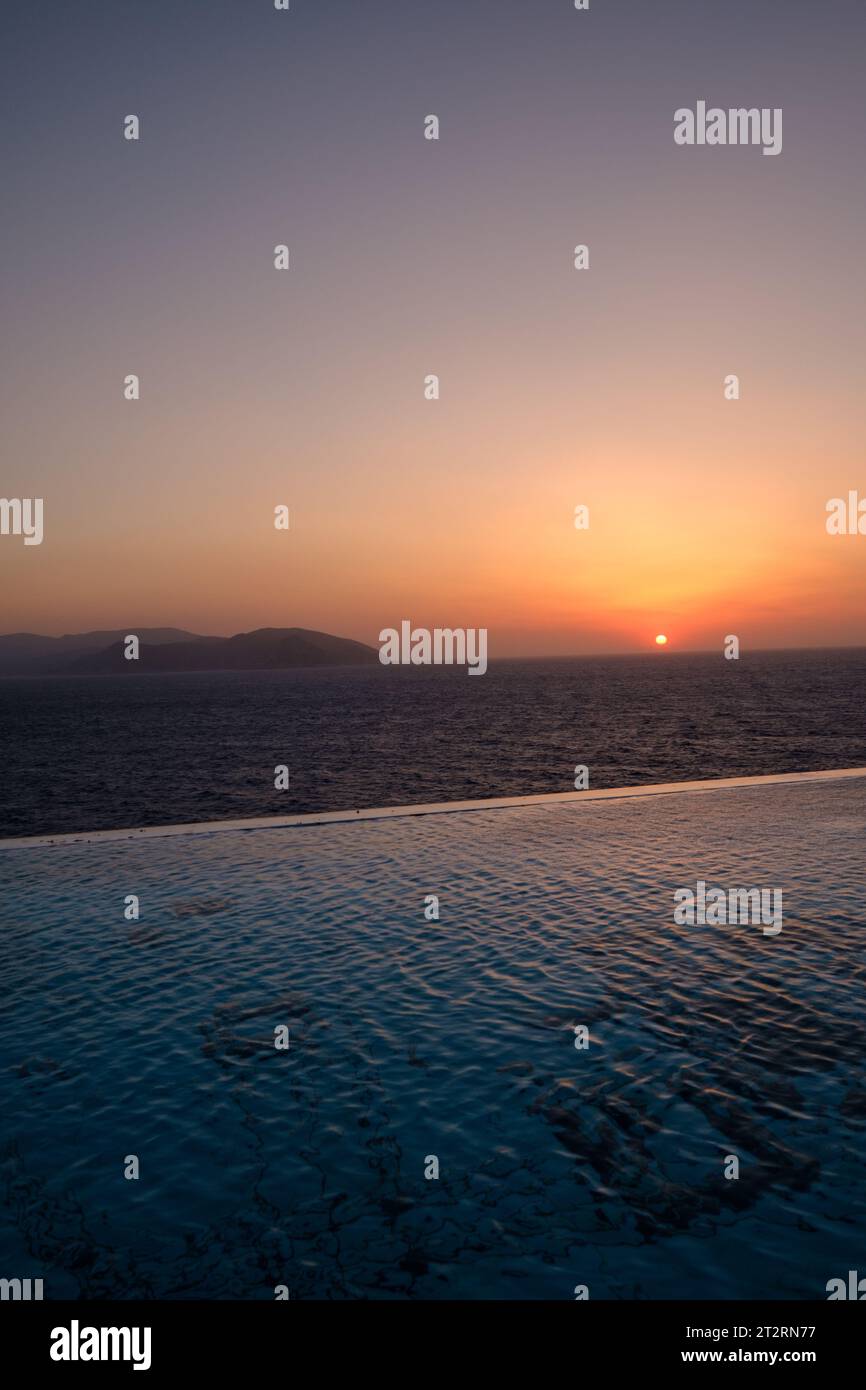 Vista panoramica di una piscina con vista sul Mar Egeo e un tramonto mozzafiato a iOS Grecia Foto Stock
