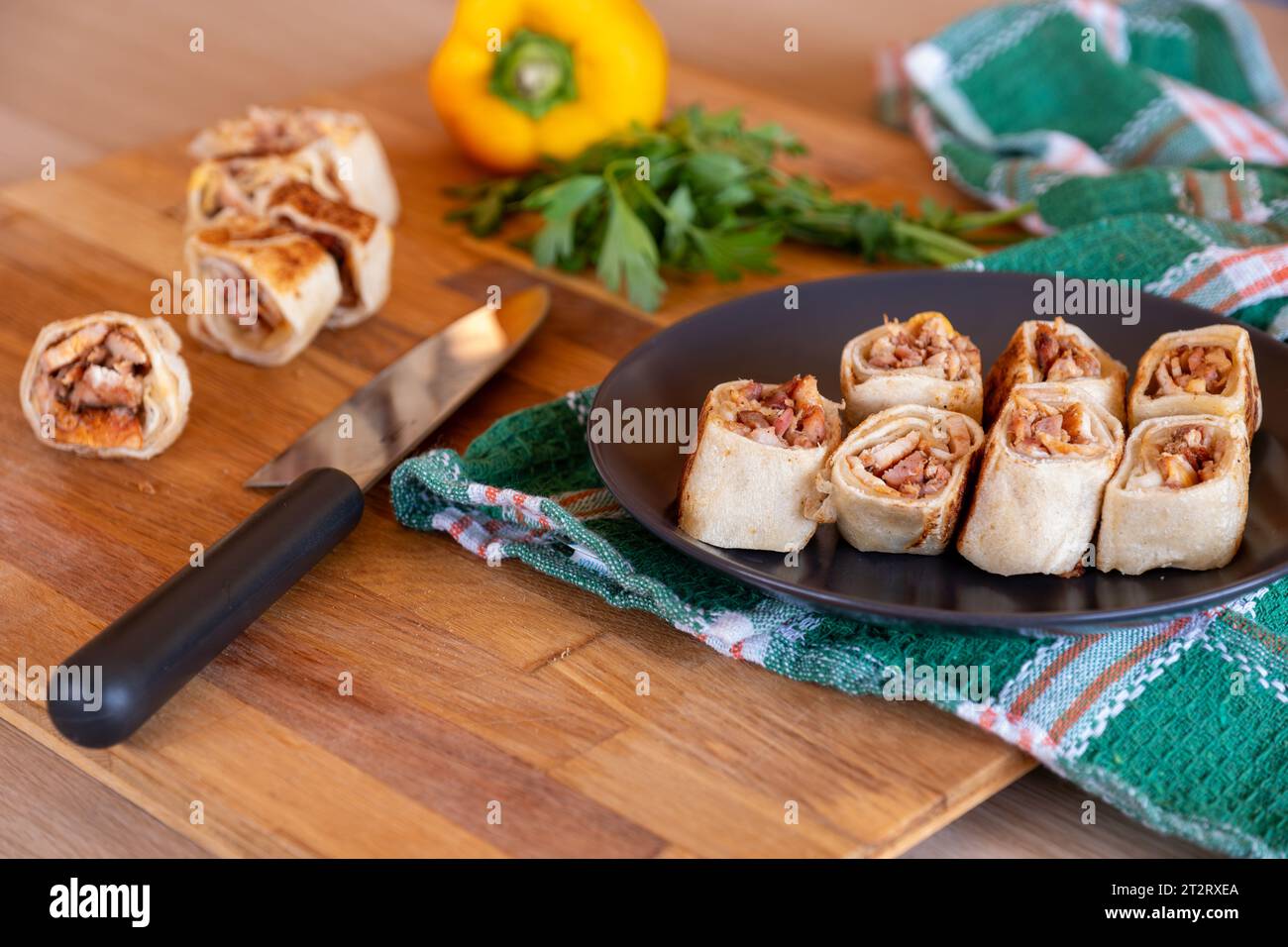 Pezzi di shawarma su tavola di legno con peperoni dolci sullo sfondo e coltello Foto Stock