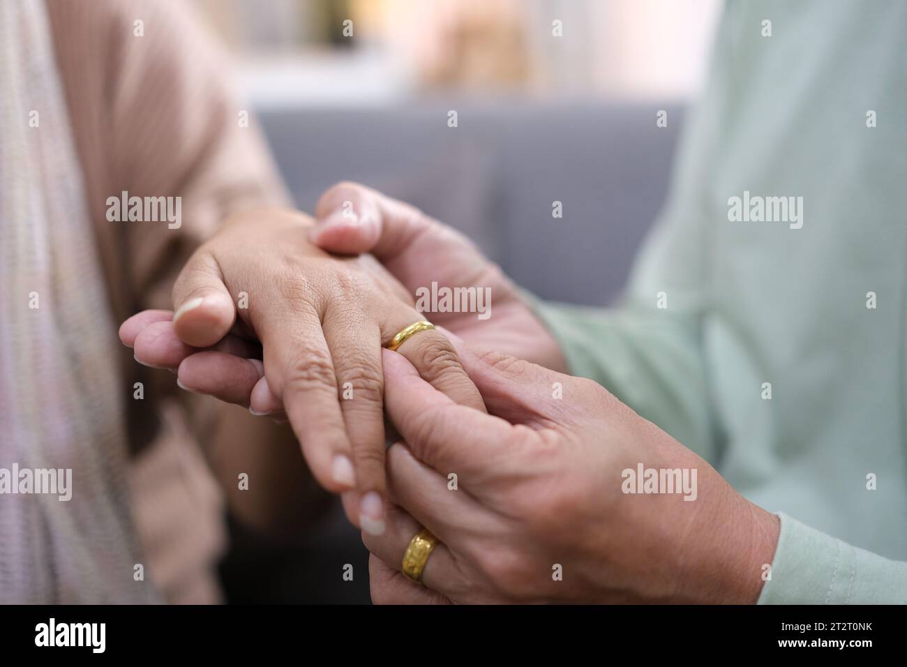 Vista ravvicinata di un vecchio uomo degli anni '60 che ha messo l'anello di fidanzamento nuziale sul dito della mano della donna amata, la coppia matura degli anni '50 fidanzata condivide un momento romantico molto tenero Foto Stock