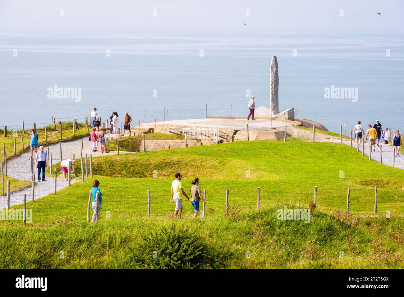 I turisti passeggiano lungo il percorso della Pointe du hoc tra i crateri delle bombe e il monumento ai ranger eretto in onore del sacrificio delle truppe americane il giorno del D Day. Foto Stock