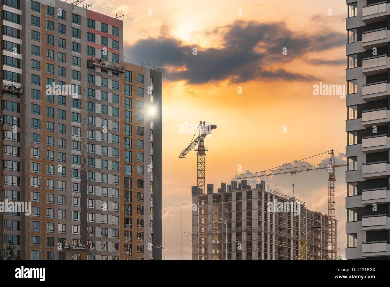Cantiere al tramonto. Alti e moderni appartamenti e gru edile. Foto Stock