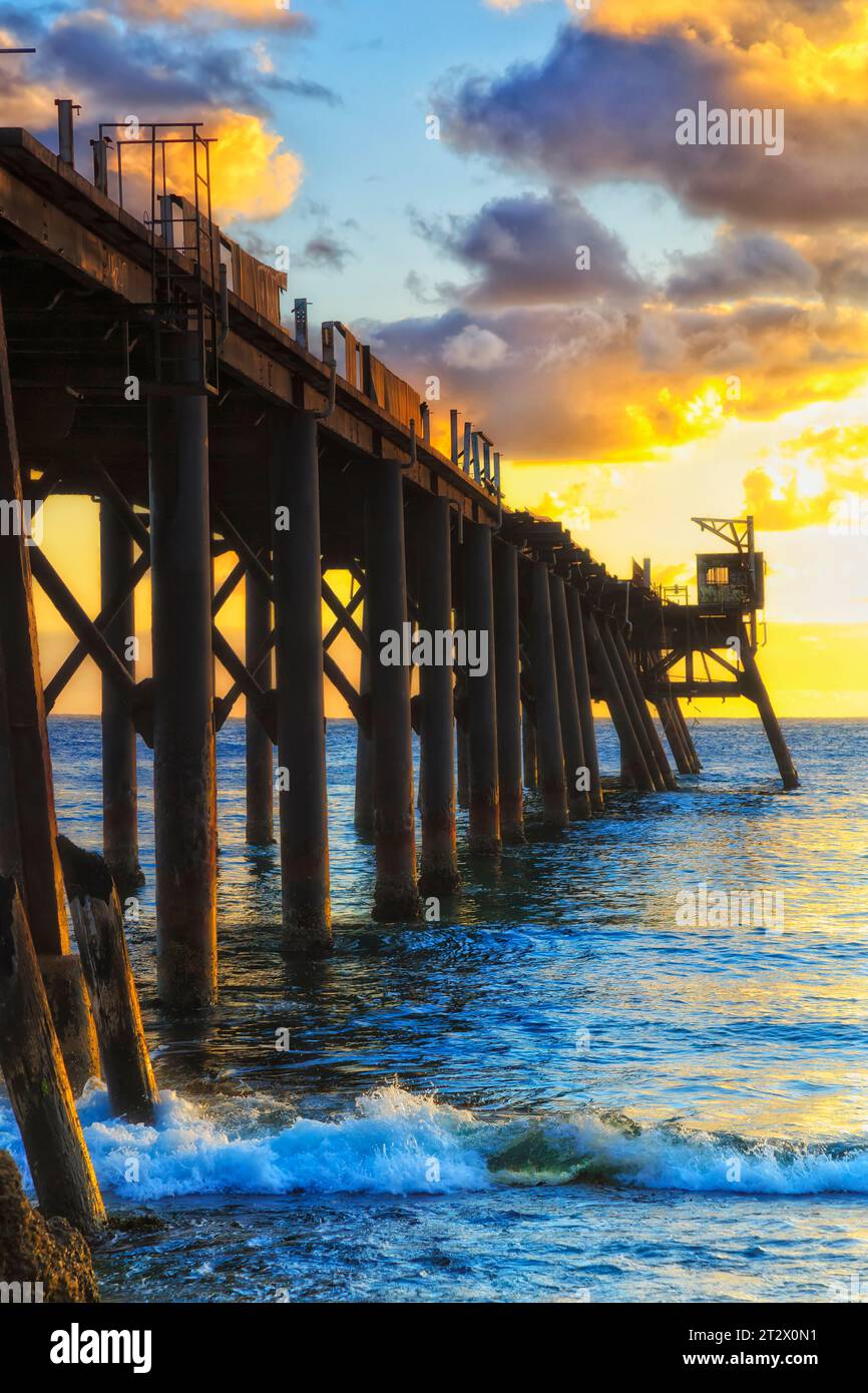 Luce soffusa su un molo storico in legno strutturato sulla costa pacifica dell'Australia. Foto Stock