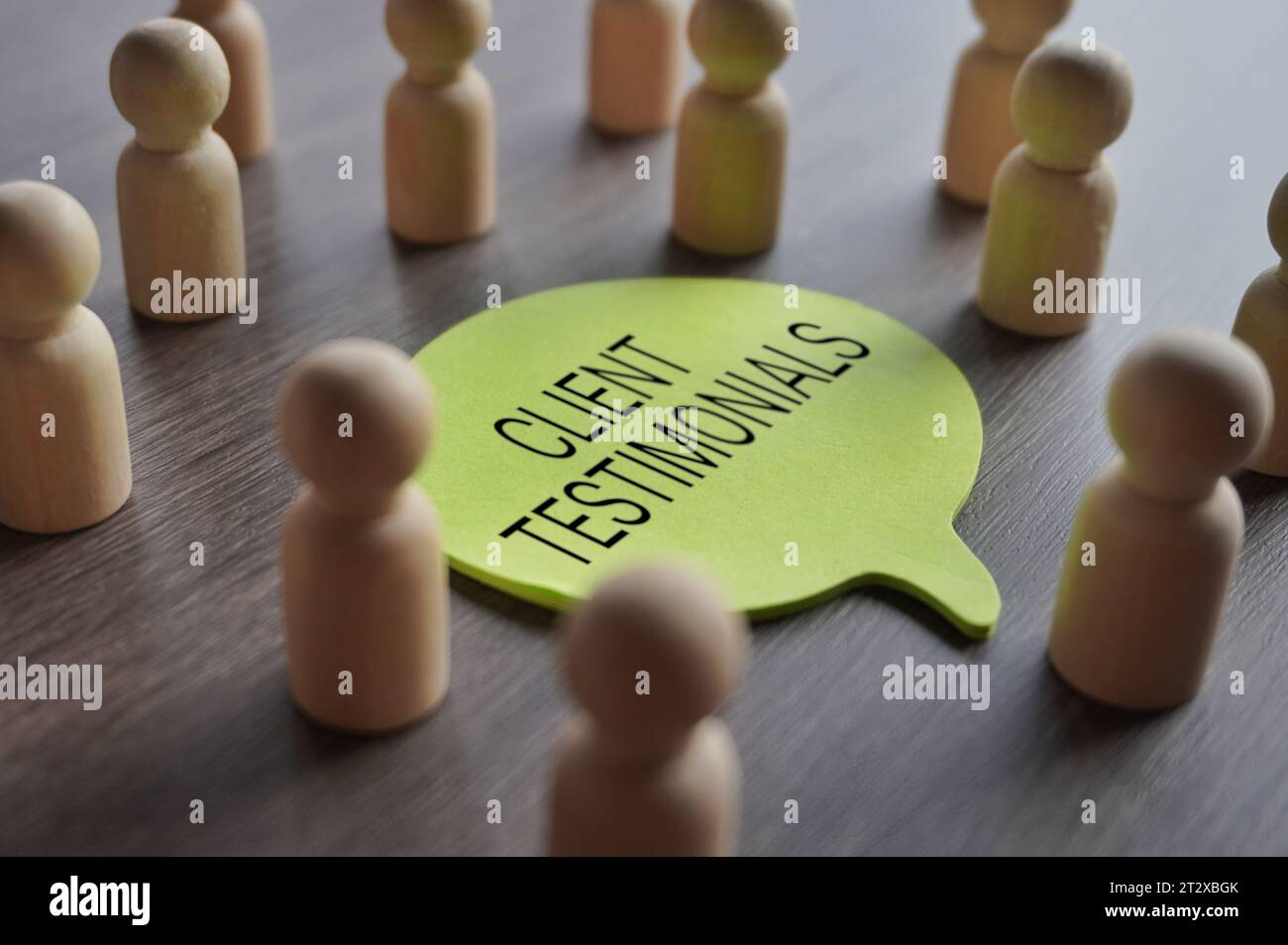 Un gruppo di statuette di legno che circondano un fumetto con TESTIMONIANZE testuali DEI CLIENTI. Business, concetto di feedback Foto Stock