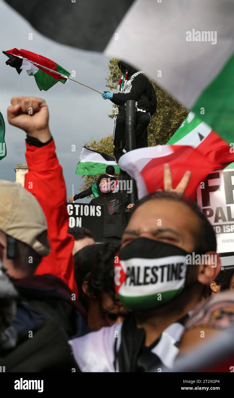 I manifestanti pro-palestinesi si riuniscono per ascoltare i discorsi di sostegno fuori Downing Street One sale un semaforo e sventola una bandiera palestinese. I sostenitori della Palestina si riuniscono per marciare verso Downing Street a seguito dei bombardamenti israeliani e della minaccia di un'invasione terrestre a Gaza da parte delle forze israeliane. Questa è la seconda settimana consecutiva che più di 100.000 persone sono scese per le strade di Londra per protestare. Molte delle organizzazioni coinvolte chiedono un cessate il fuoco, l'apertura del valico di Rafah in Egitto e la concessione di aiuti umanitari nella Striscia di Gaza. Foto Stock