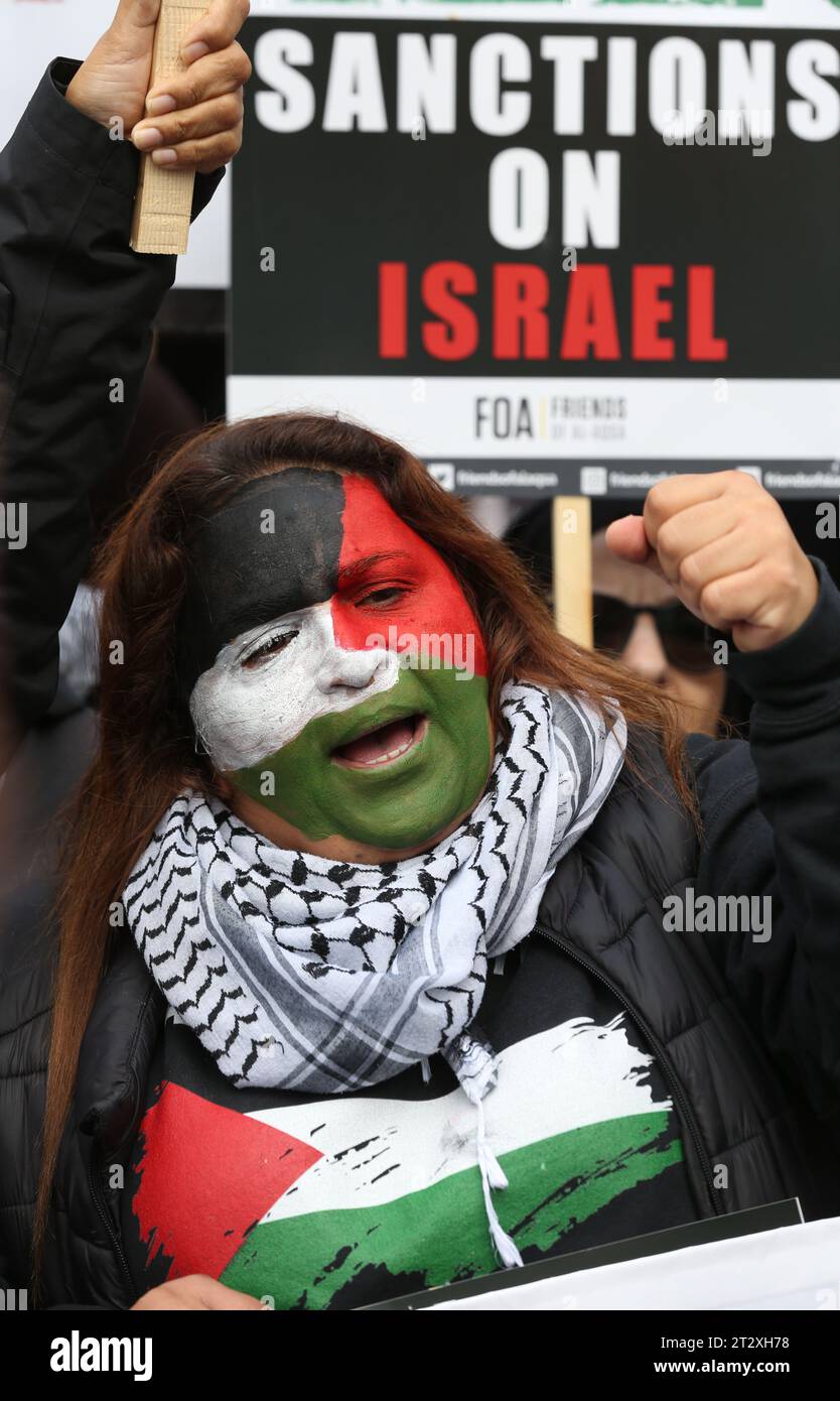 I manifestanti pro-palestinesi si riuniscono, una ha il suo volto dipinto con una bandiera palestinese un’altra porta un cartello con la scritta “sanzioni contro Israele”, mentre marciano attraverso Londra. I sostenitori della Palestina si riuniscono per marciare verso Downing Street a seguito dei bombardamenti israeliani e della minaccia di un'invasione terrestre a Gaza da parte delle forze israeliane. Questa è la seconda settimana consecutiva che più di 100.000 persone sono scese per le strade di Londra per protestare. Molte delle organizzazioni coinvolte chiedono un cessate il fuoco, l'apertura del valico di Rafah in Egitto e l'autorizzazione agli aiuti umanitari Foto Stock