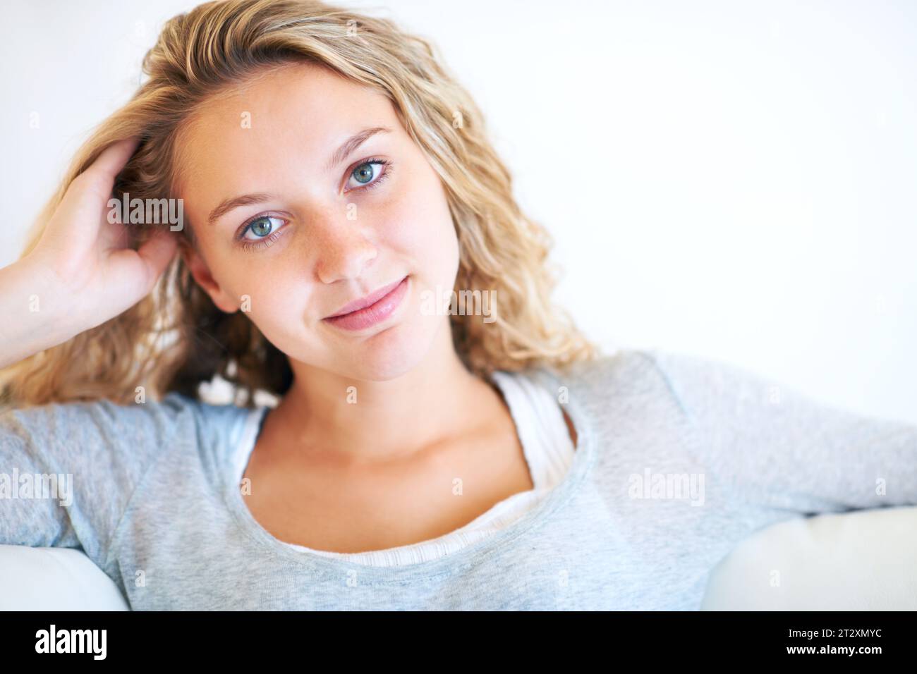 Donna, ritratto e relax sul divano a casa per la pace, la mattinata lenta o il weekend confortevole. Persona femminile, viso e sorriso morbido, sicurezza o calma Foto Stock