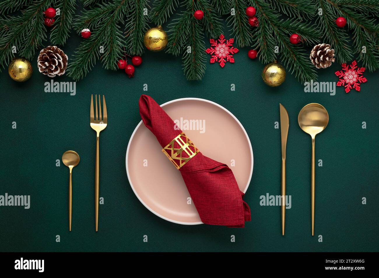 Piatto vuoto, posate dorate. Ambiente da tavolo per le feste, decorazioni natalizie. Festeggiamenti per la vigilia di Natale: Sistemazione piatta. Rosso, accento oro. Bauble lucenti, fi Foto Stock