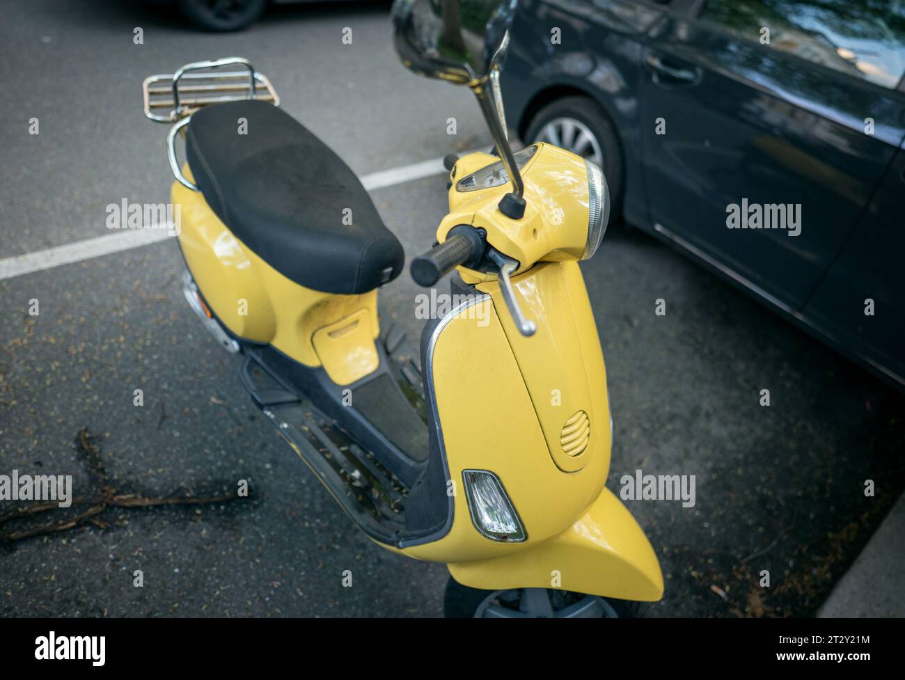 Scooter giallo parcheggiato in un parcheggio grigio Foto Stock