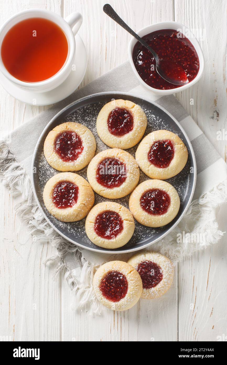 Eseguire un'anteprima di un impasto burroso e friabile alla vaniglia, ripieno di deliziosa marmellata di lamponi croccanti, primo piano sul piatto servito con tè sulla W bianca Foto Stock