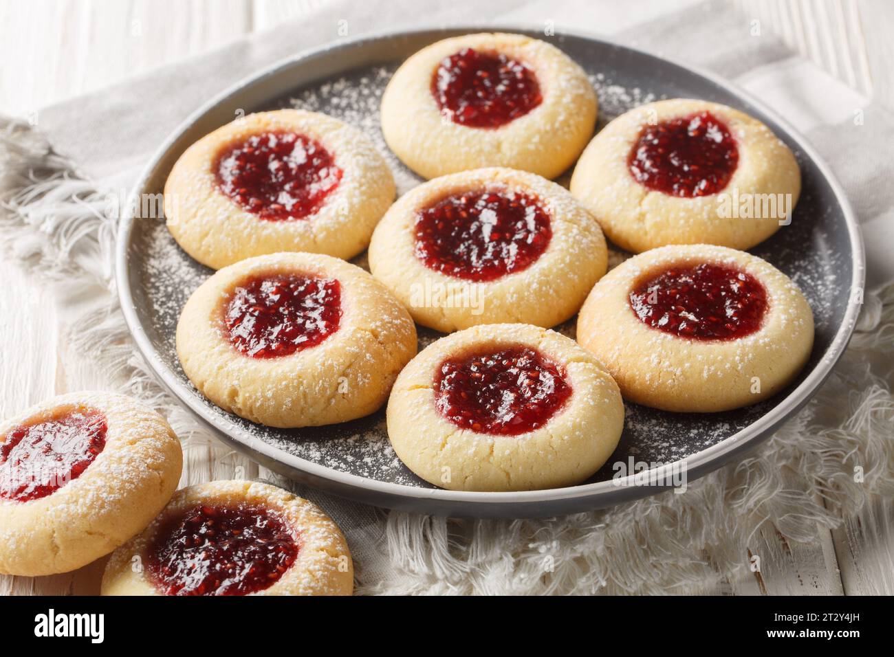 Primo piano sui biscotti Hallongrottor Swedish Thumbprint sul piatto sul tavolo di legno bianco. Orizzontale Foto Stock