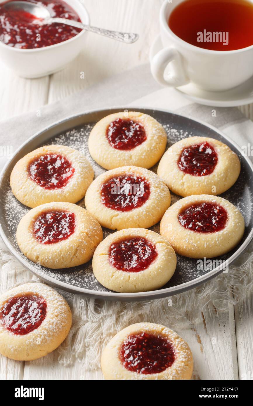 Eseguire un'anteprima di un impasto burroso e friabile alla vaniglia, ripieno di deliziosa marmellata di lamponi croccanti, primo piano sul piatto servito con tè sulla W bianca Foto Stock
