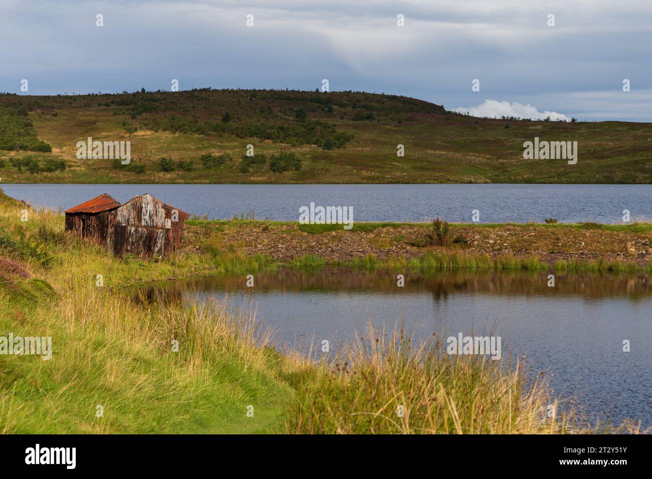 Una rovina di una baracca ai margini di un lago in Scozia in una soleggiata mattinata estiva durante una mattinata estiva Foto Stock
