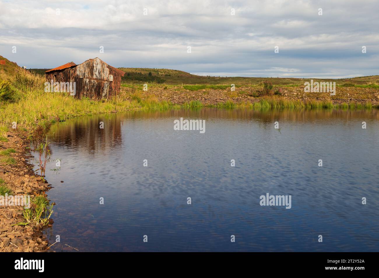 Una rovina di una baracca ai margini di un lago in Scozia in una soleggiata mattinata estiva durante una mattinata estiva Foto Stock