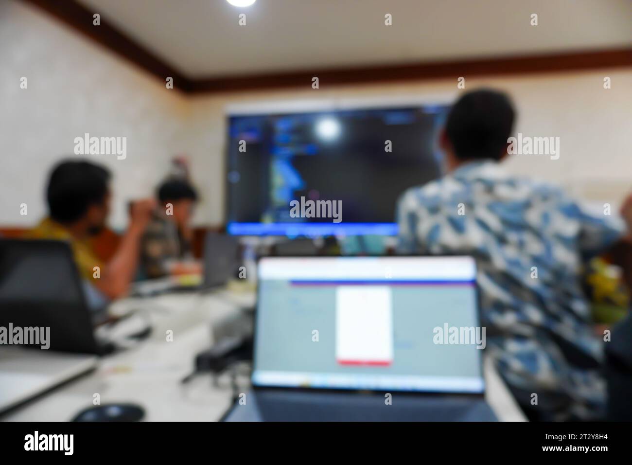 un gruppo di impiegati si è riunito intorno a un tavolo da conferenza, le loro figure sono elegantemente sfocate mentre si impegnano nell'attenta osservazione di un team Foto Stock