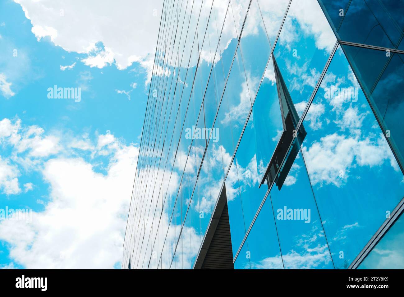 Vetro a finestra aperta in un edificio a più piani che riflette l'incantevole cielo blu nuvoloso Foto Stock