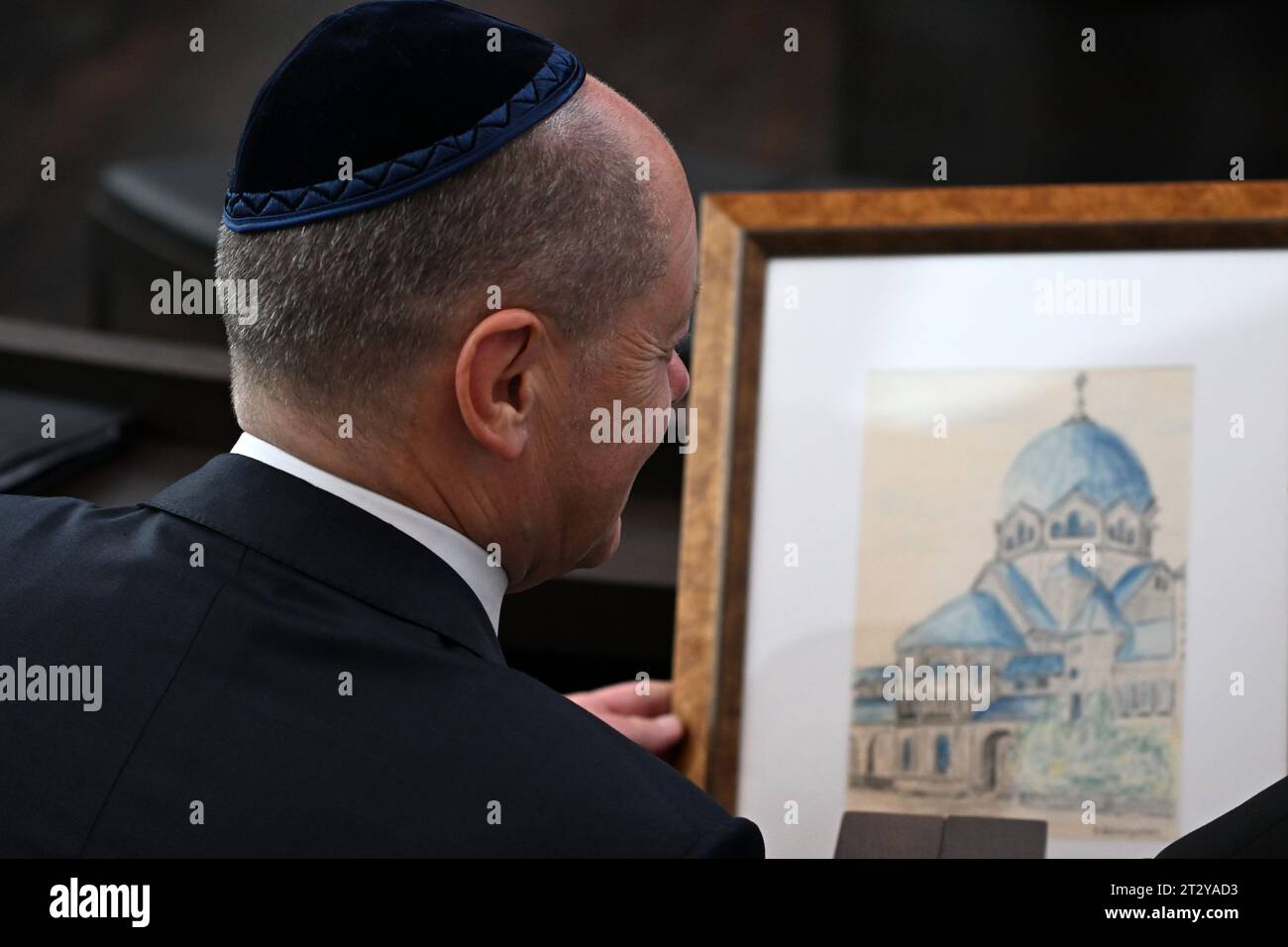 22 ottobre 2023, Sassonia-Anhalt, Dessau-Roßlau: Inaugurazione della sinagoga di nuova costruzione a Dessau-Roßlau, il cancelliere Olaf Scholz (SPD) guarda, una copia di un disegno storico della vecchia sinagoga di Dessau. La sinagoga completa la casa del rabbino, costruita nel 1908 e ora un edificio storico, dove Kurt Weill trascorse gli anni dell'infanzia, poiché suo padre Albert Weill era cantore della congregazione. La vita religiosa e culturale della comunità ebraica di Dessau, che è stata fondata trent'anni fa, si è finora svolta nello spazio molto limitato della Casa del rabbino. Con la sinagoga di Weill, il Foto Stock