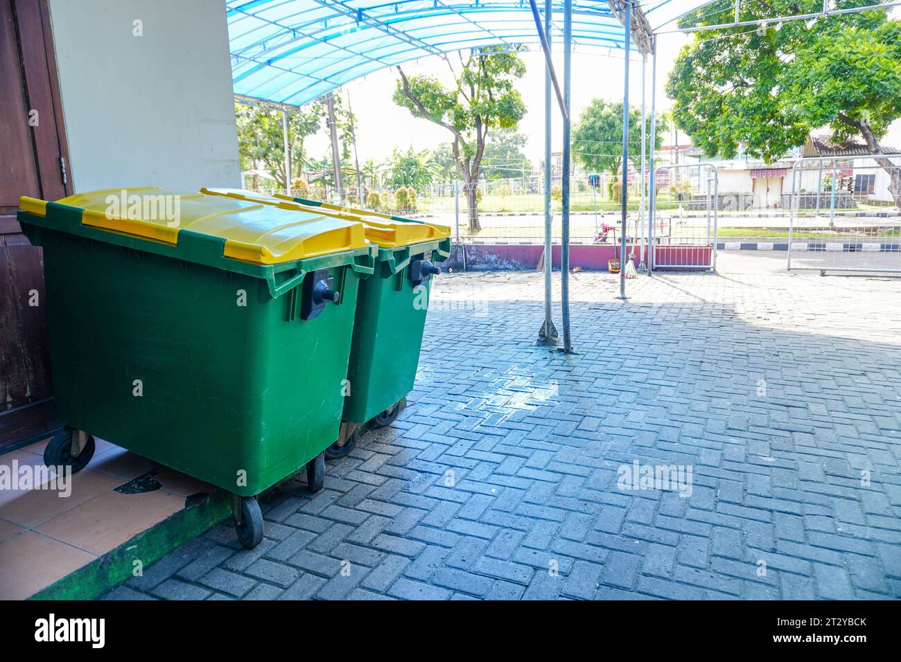 Stoccaggio organizzato all'aperto: Contenitori per rifiuti in plastica verde nel cortile interno Foto Stock
