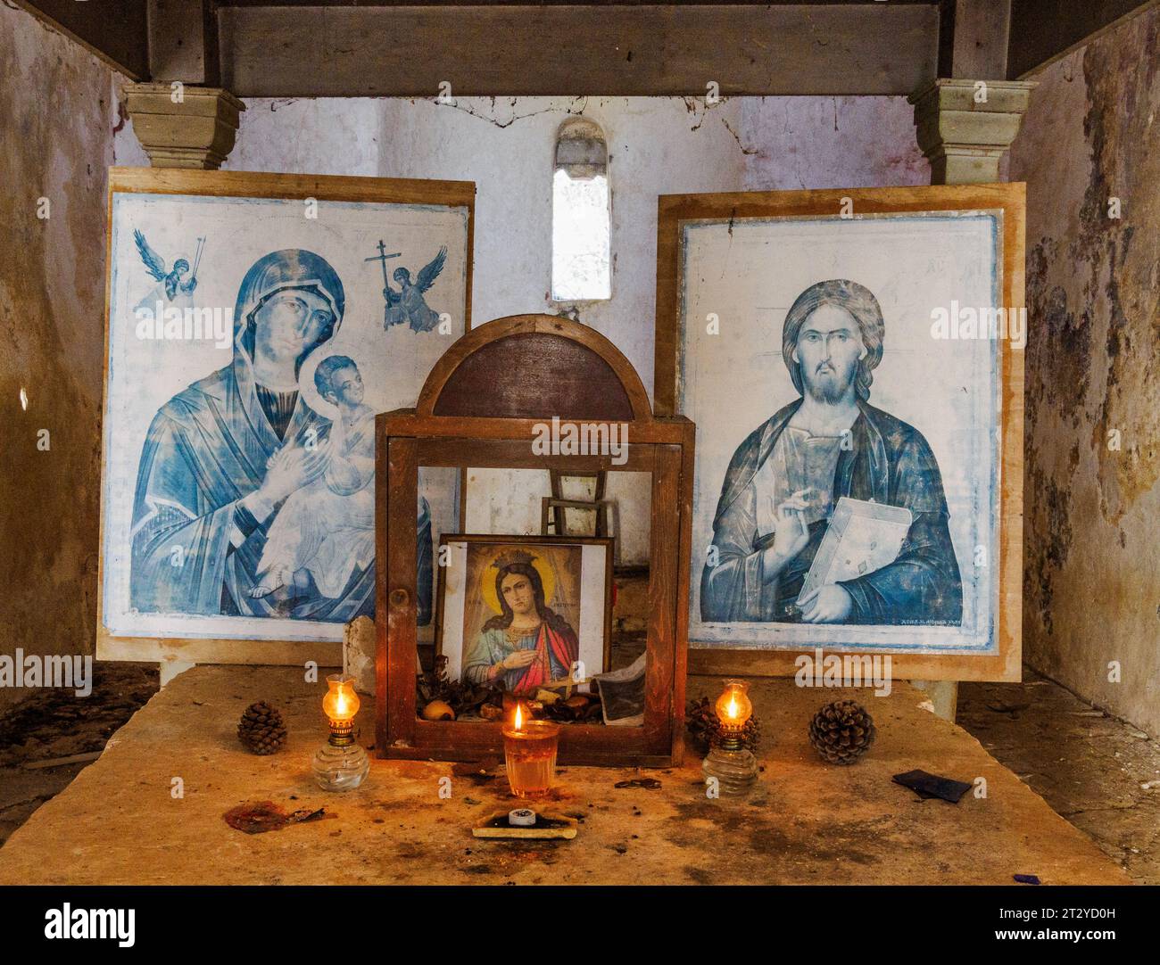 Icone cristiane su candele accese sull'altare di Agia Ekaterini, un monastero abbandonato e in rovina sulla costa settentrionale di Corfù in Grecia Foto Stock