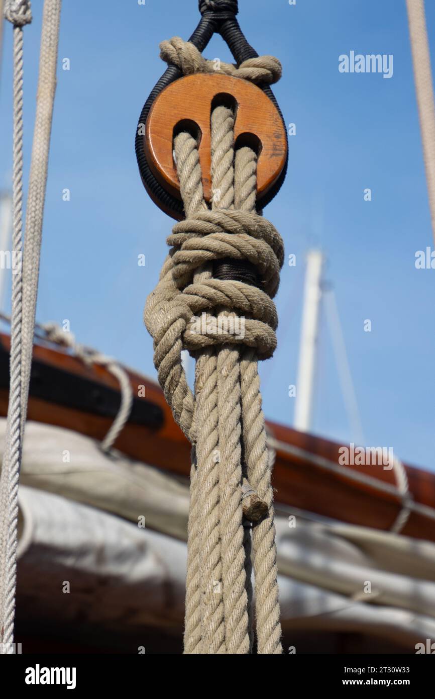 Primo piano di una puleggia di legno con le corde di una classica barca a vela Foto Stock