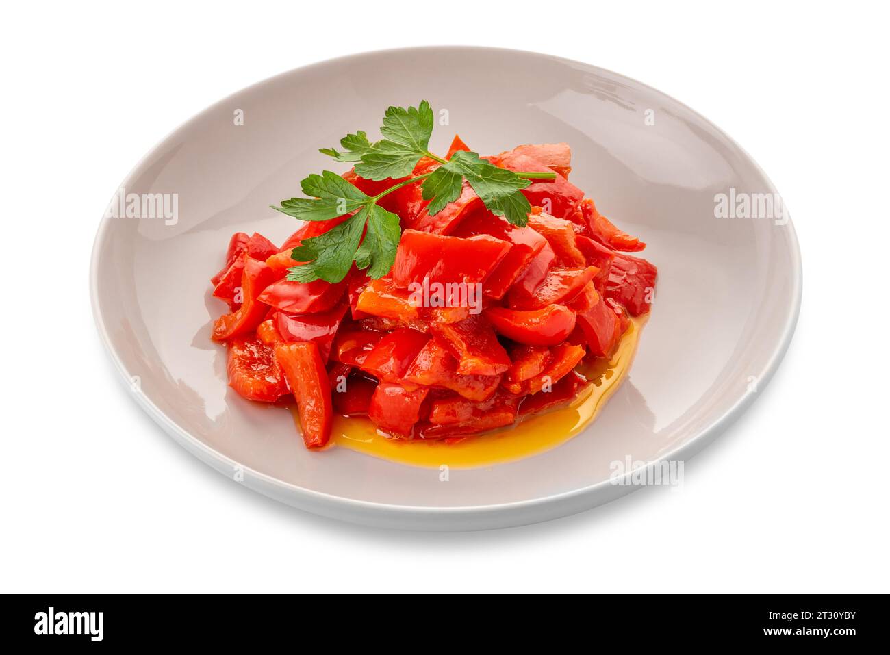 Peperoni rossi cotti a pezzi conditi con olio d'oliva e foglie di prezzemolo - peperonata in piatto bianco isolato su bianco con percorso di ritaglio incluso Foto Stock