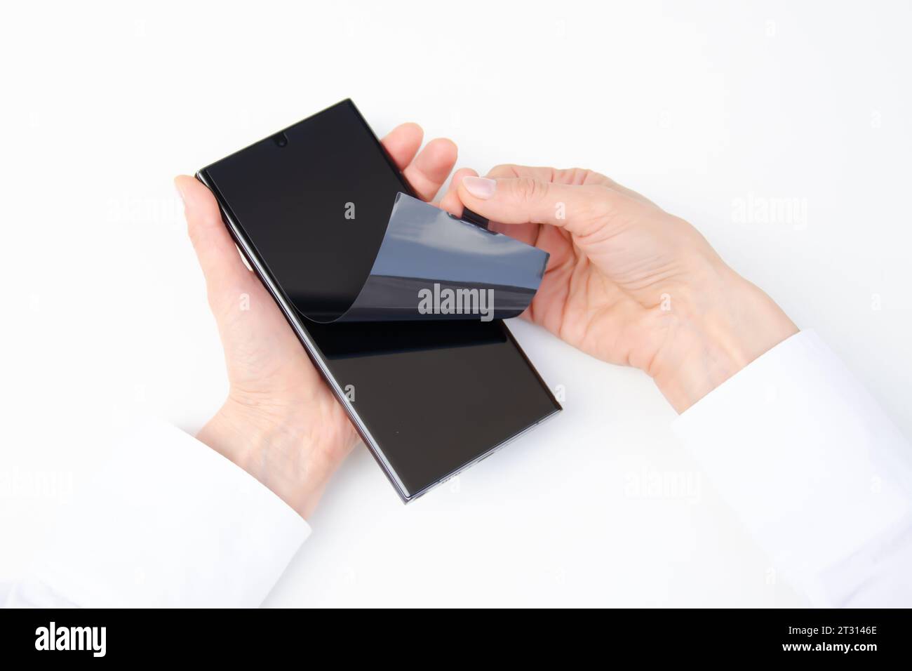 Disimballare il nuovo smartphone. Rimozione della pellicola protettiva nera da un nuovo telefono. Primo piano delle mani di una donna. Sfondo bianco. Smartphone samsung Galaxy S23 Foto Stock