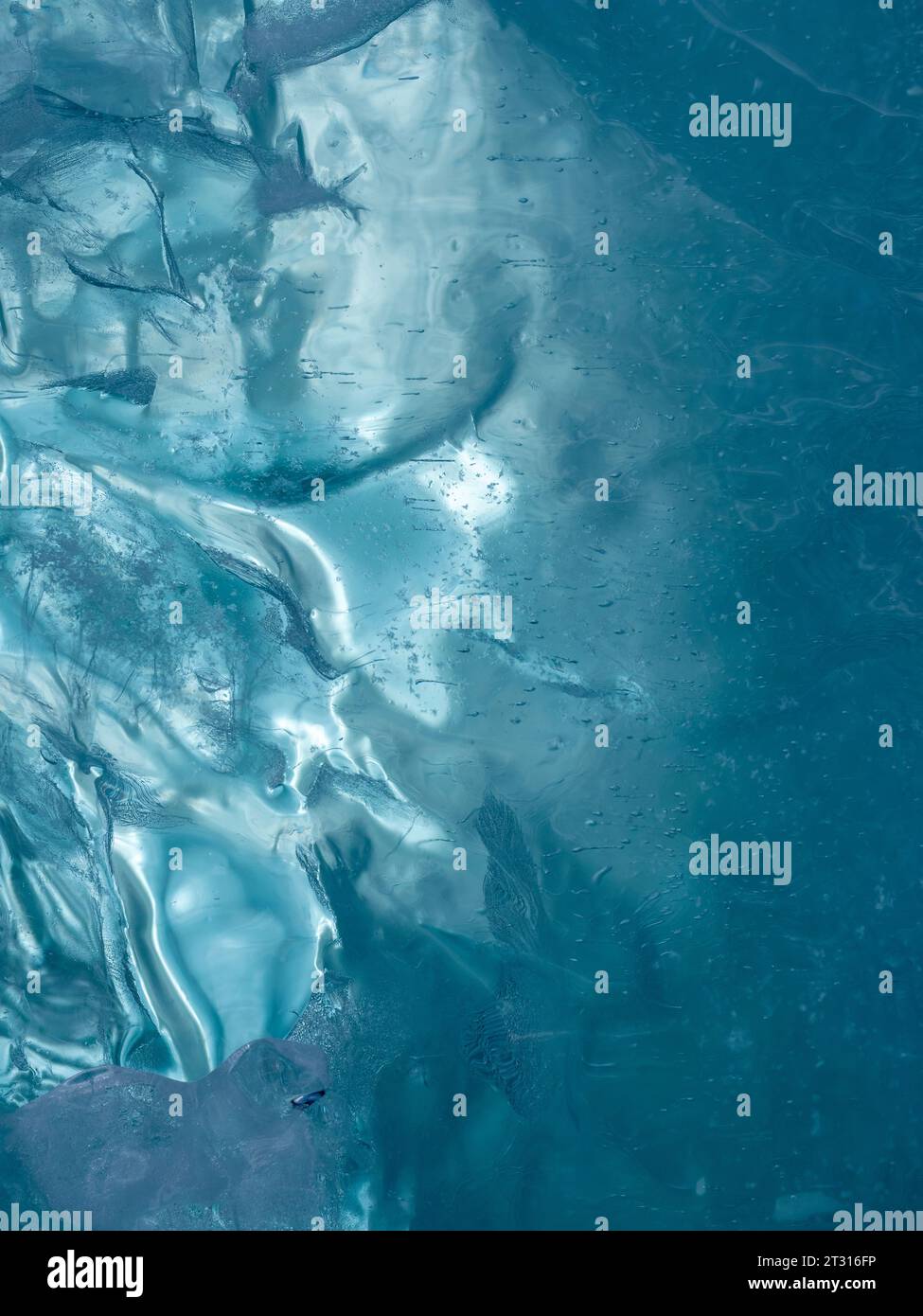 Consistenza di ghiaccio ghiacciato di un lago di montagna. Spessore del ghiaccio verde-blu attraverso il quale è visibile la luce Foto Stock