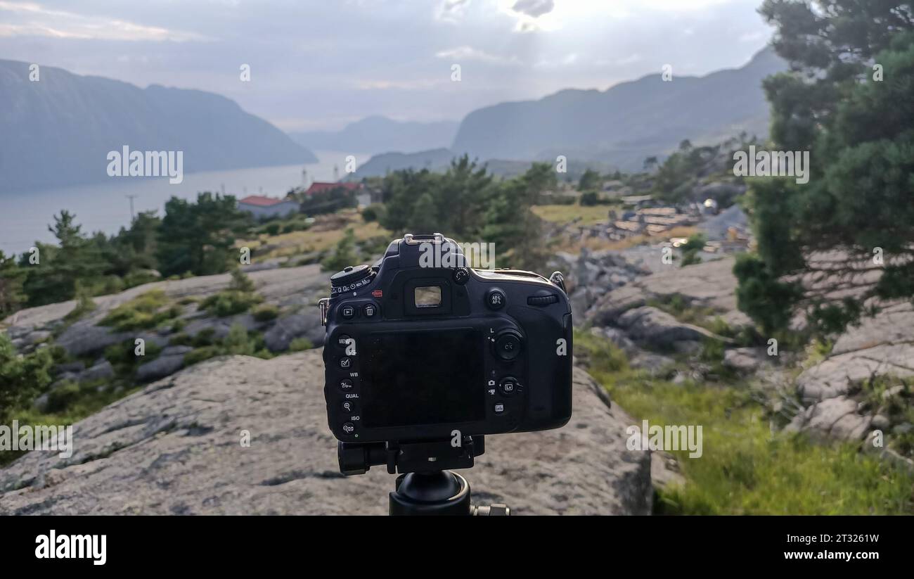 Macchina fotografica semi professionale su un cavalletto pronta a scattare una foto di un bellissimo fiordo norvegese. Foto Stock