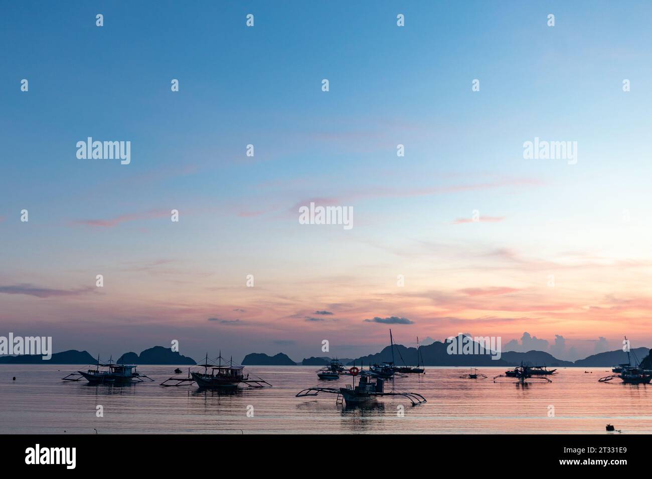 Tradizionali battelli filippini banca con balenieri ancorati al tramonto in un paradiso tropicale Foto Stock