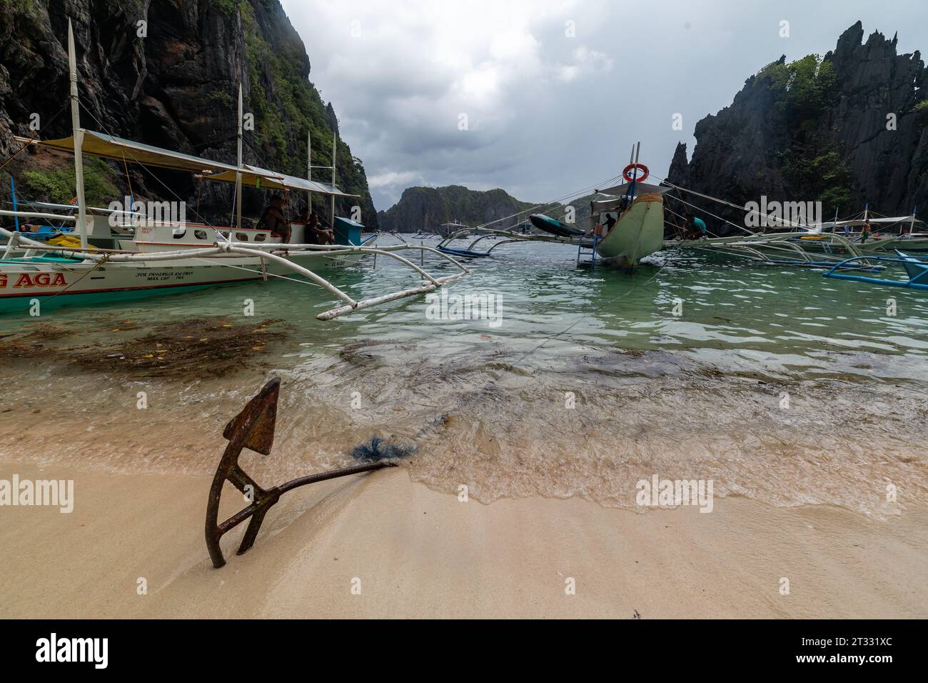 Tradizionali battelli filippini banca con balenieri ancorati sulla spiaggia nella baia circondata da pinnacoli di roccia Foto Stock