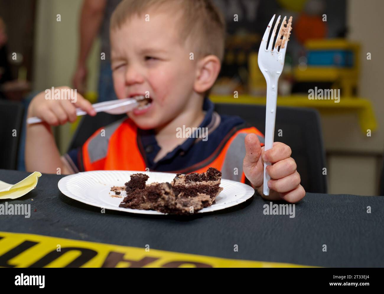 Il piccolo bambino seduto al tavolo a mangiare una torta Foto Stock