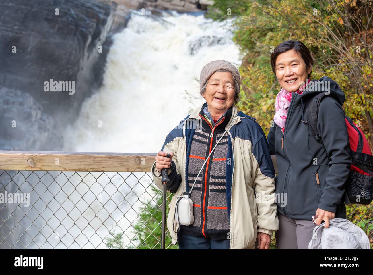 Anziana donna cinese e figlia in posa per le foto di fronte alle cascate del Canyon Sainte-Anne. Quebec. Canada. Foto Stock