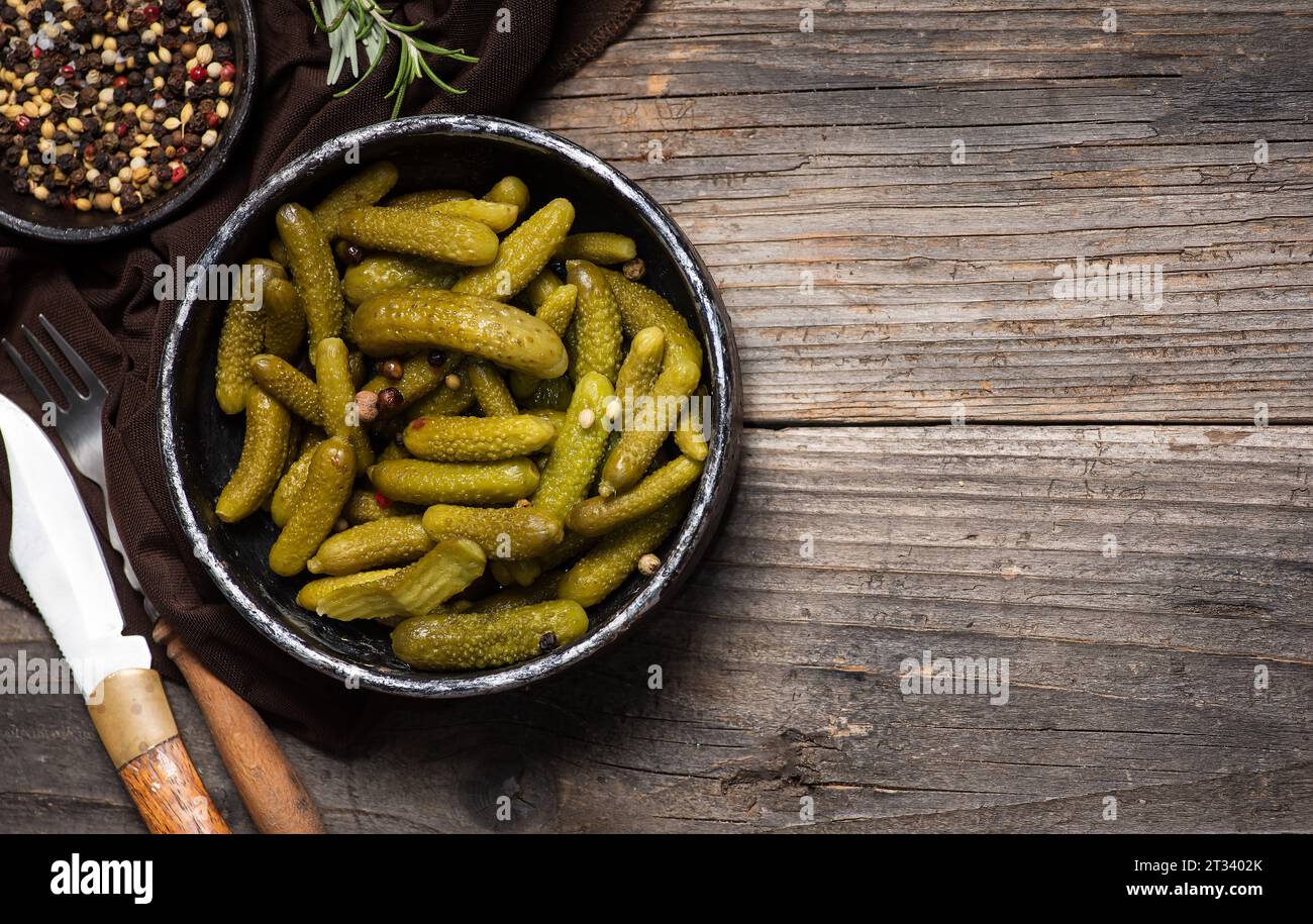Sottaceti o cetriolini verdi in una ciotola su un tavolo di legno. Deliziosa insalata invernale Foto Stock