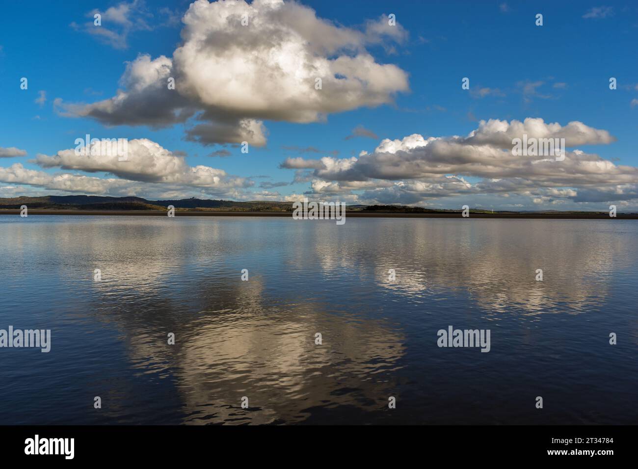 Nuvole e un cielo blu che si riflettono sulla superficie dell'acqua. Foto Stock