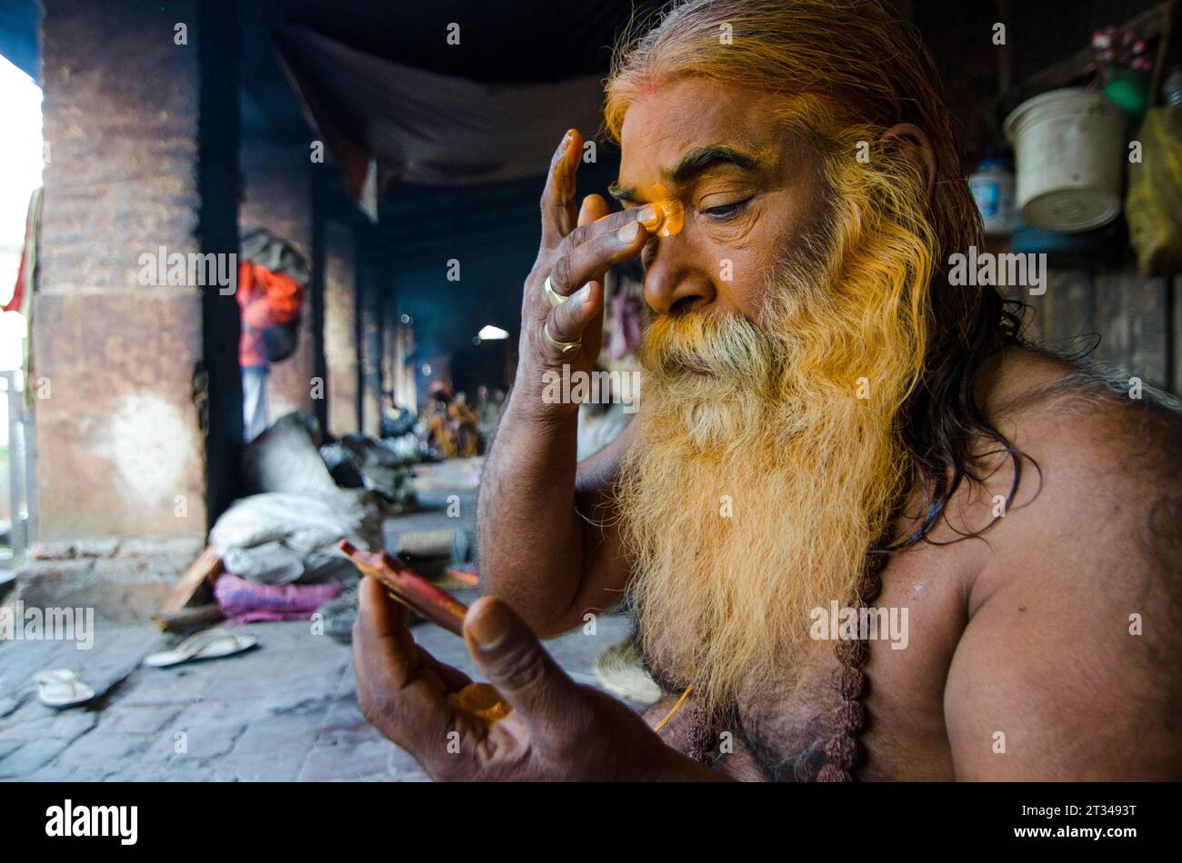 Un uomo santo indù shaivita applica la colorazione simbolica al suo volto al Tempio di Pashupatinath, Nepal Foto Stock
