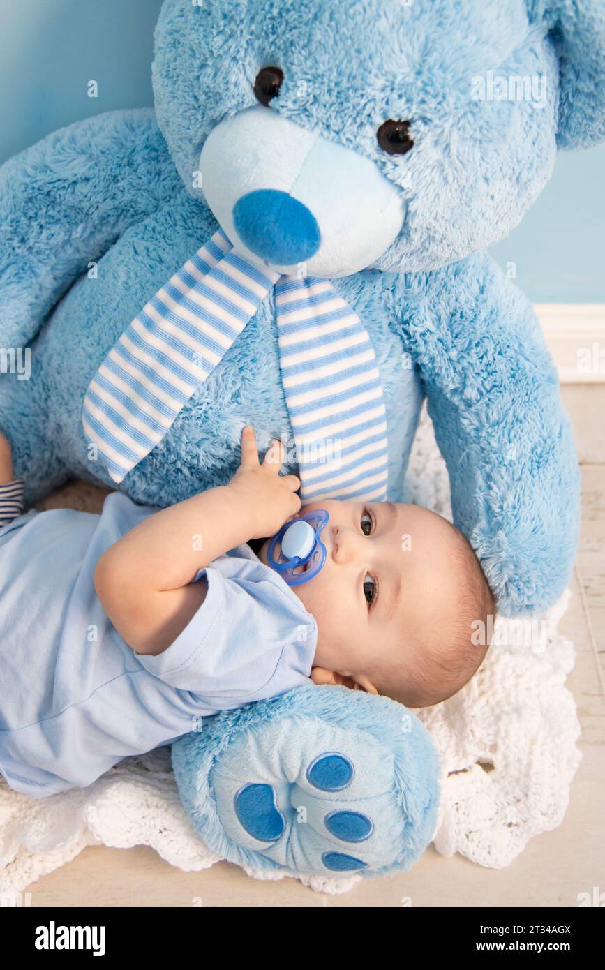 cartolina di un bellissimo bambino che gioca con un grande orsacchiotto blu Foto Stock