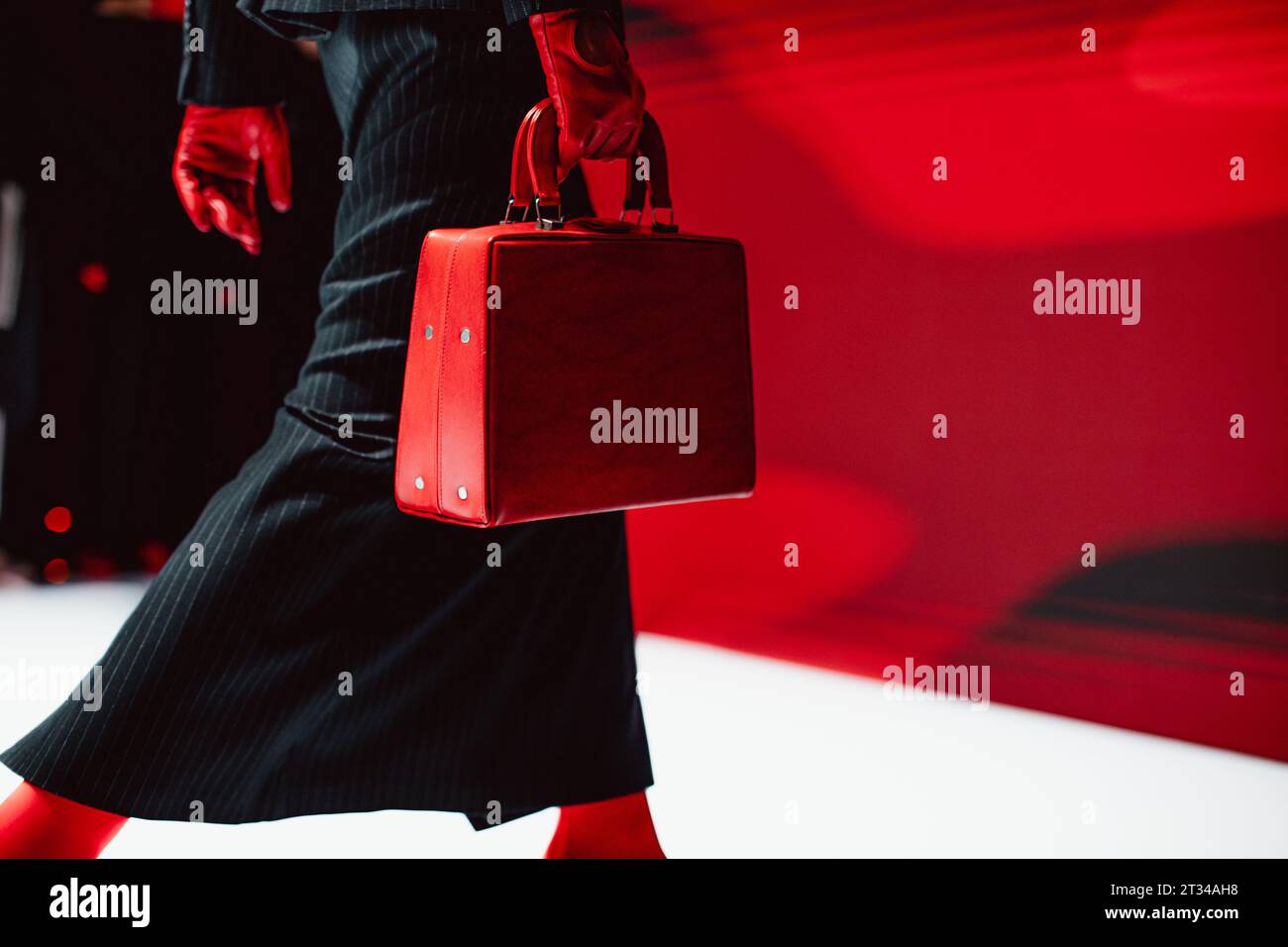 Dettagli alla moda di gonna lunga nera, guanti rossi e borsa in pelle. Modella di moda che cammina sulla passerella Foto Stock