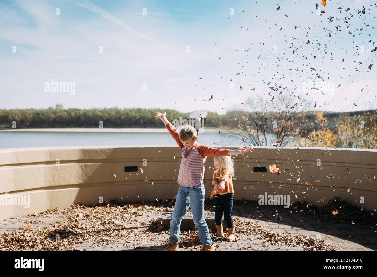 Bambini che gettano foglie autunnali nell'aria il giorno dell'autunno Foto Stock