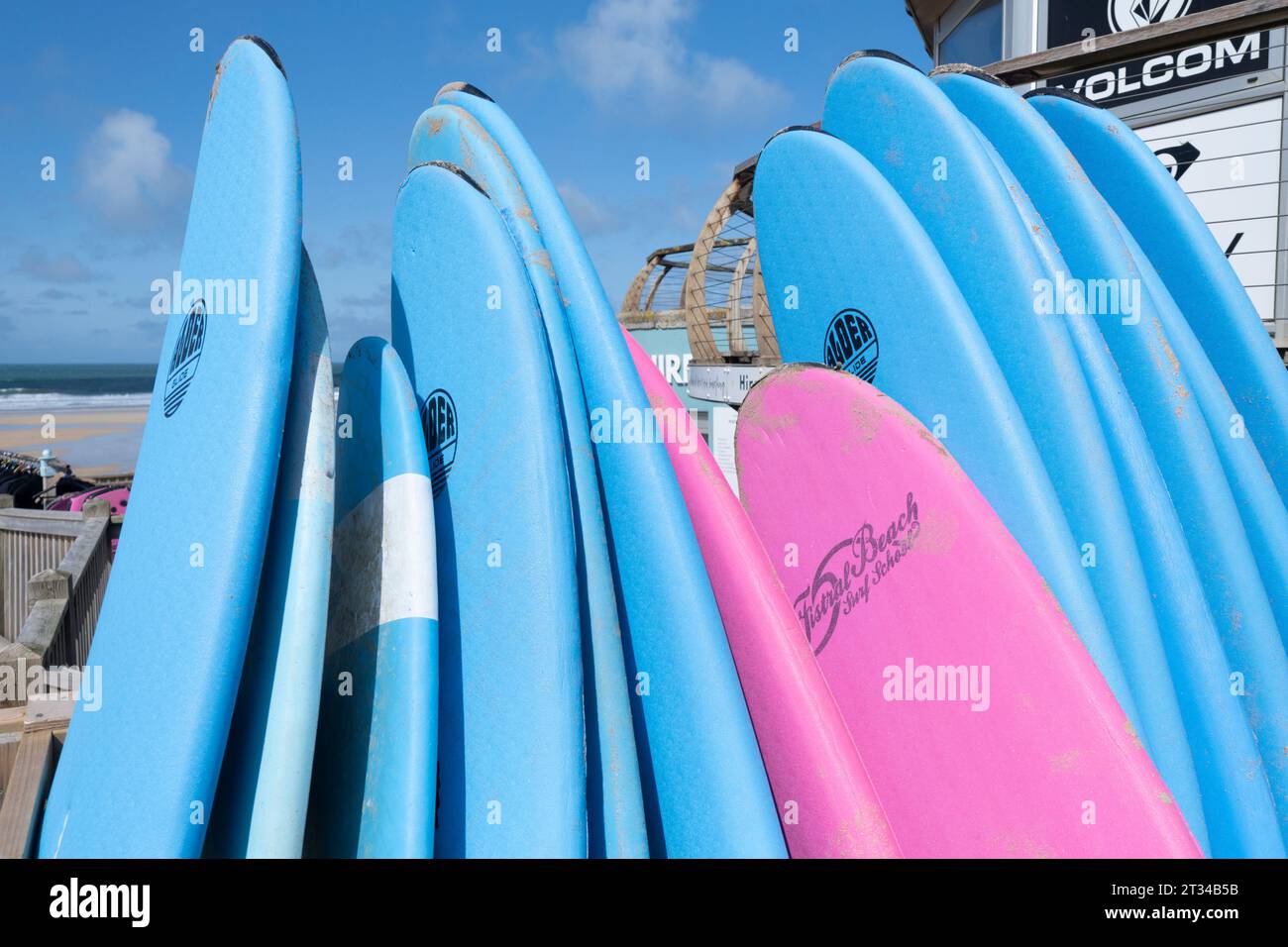 Tavole da surf colorate impilate e disponibili per il noleggio presso il negozio di surf a Fistral Beach a Newquay in Cornovaglia in Inghilterra nel Regno Unito. Foto Stock