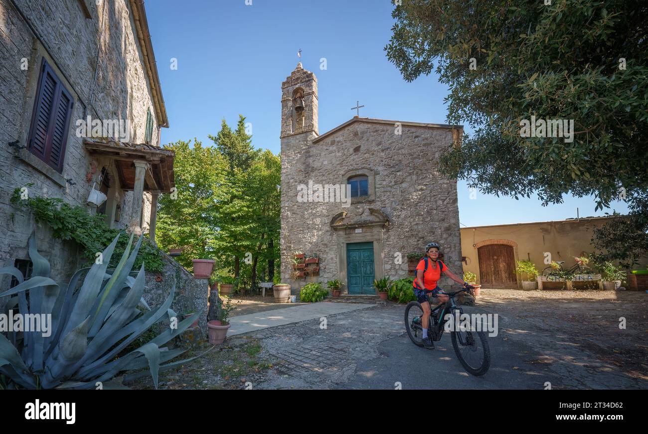 Bella donna anziana in mountain bike elettrica in un piccolo villaggio vicino a Laterina in Val Darno, Toscana, Italia Foto Stock