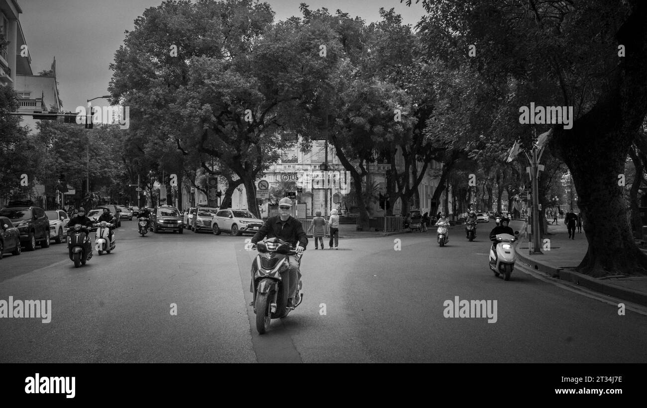 Un uomo vietnamita guida la sua motocicletta lungo le Thai per stressarsi in una giornata invernale al centro di Hanoi, in Vietnam. Foto Stock