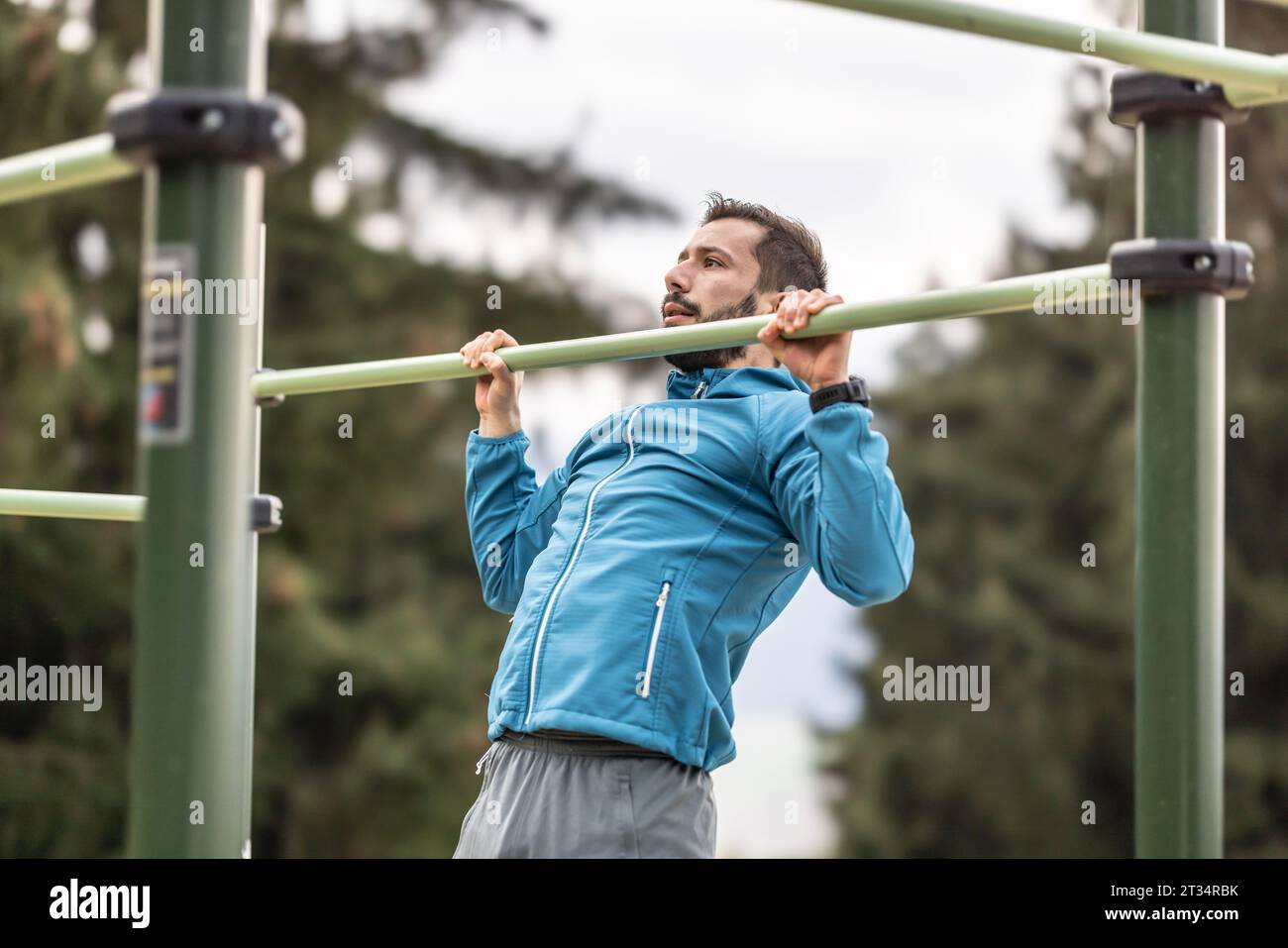 Un giovane che si occupa di ginnastica calistenica in una palestra all'aperto con barre parallele. Fa delle flessioni al bar. Concetto di stile di vita sano. Foto Stock