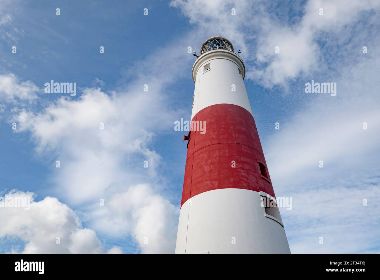 Il suggestivo faro rosso e bianco di Portland Bill, Dorset, contro un suuny cielo nuvoloso e bianco, Foto Stock