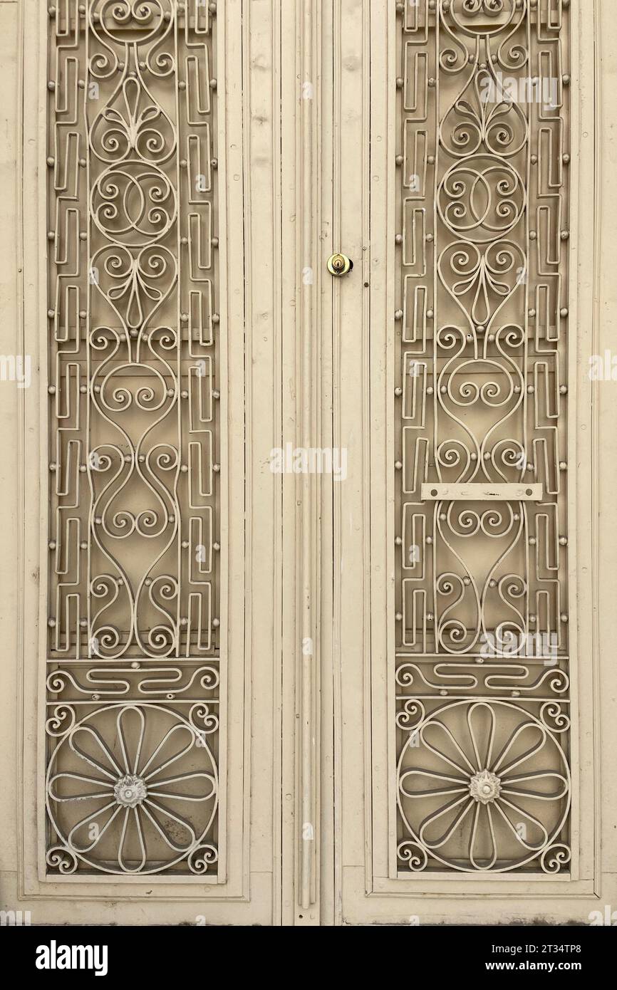 Vecchia porta pesante e doppia ala in metallo beige con ornamenti decorativi in ferro battuto, foto di primo piano delle porte chiuse di una vecchia casa Foto Stock