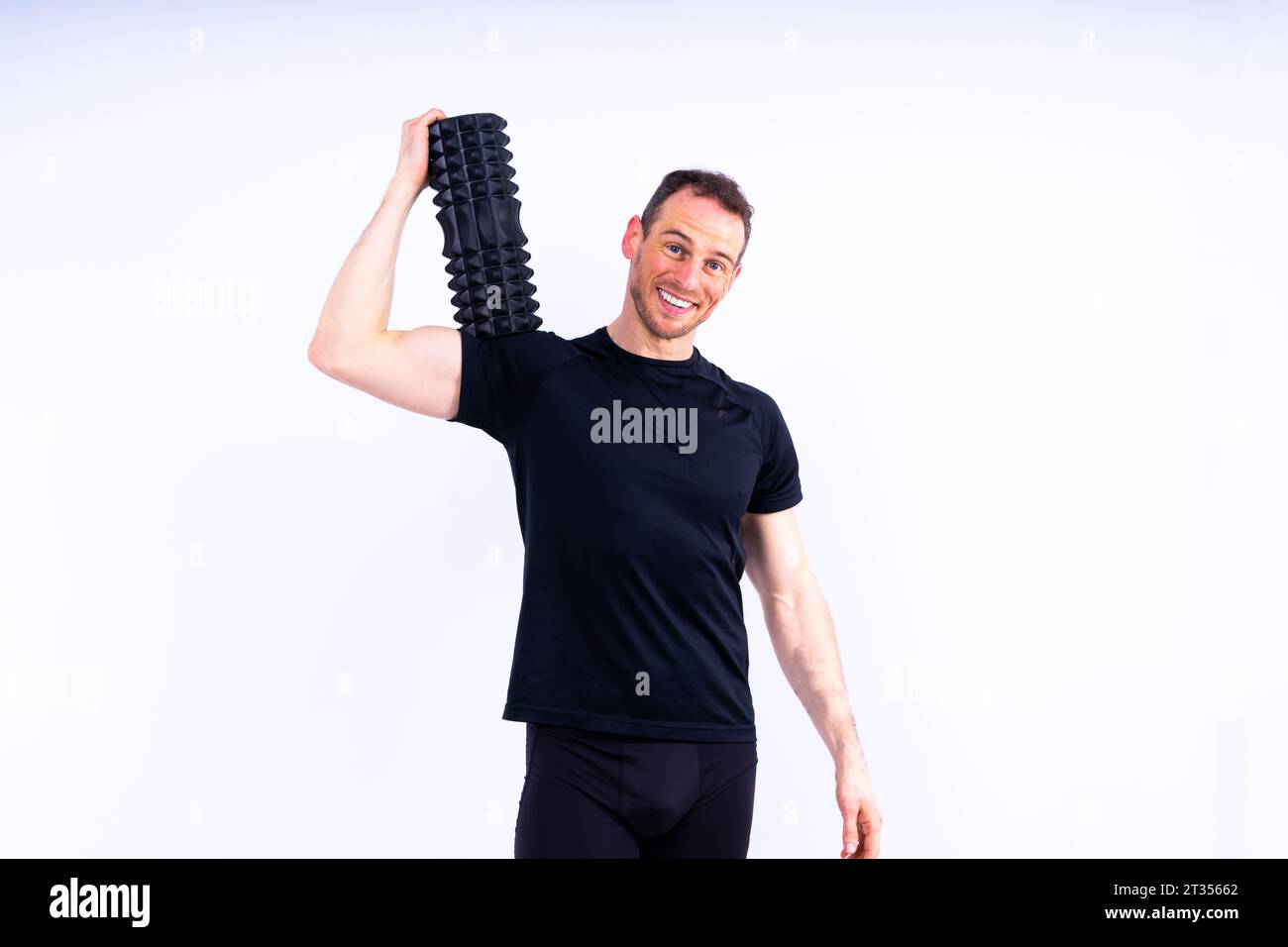 Athletic uomo usando un rullo in gomma spugna per alleviare muscoli doloranti dopo un allenamento. Foto Stock