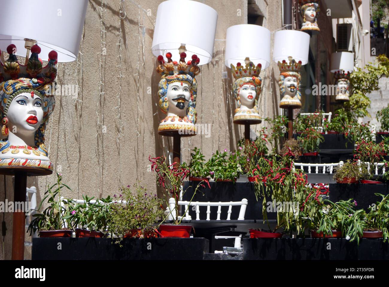 Testa di Moro (testa di Moro) dai colori vivaci teste moresche dipinte in ceramica su una parete all'esterno di un tradizionale ristorante siciliano a Taormina, in Sicilia. Foto Stock
