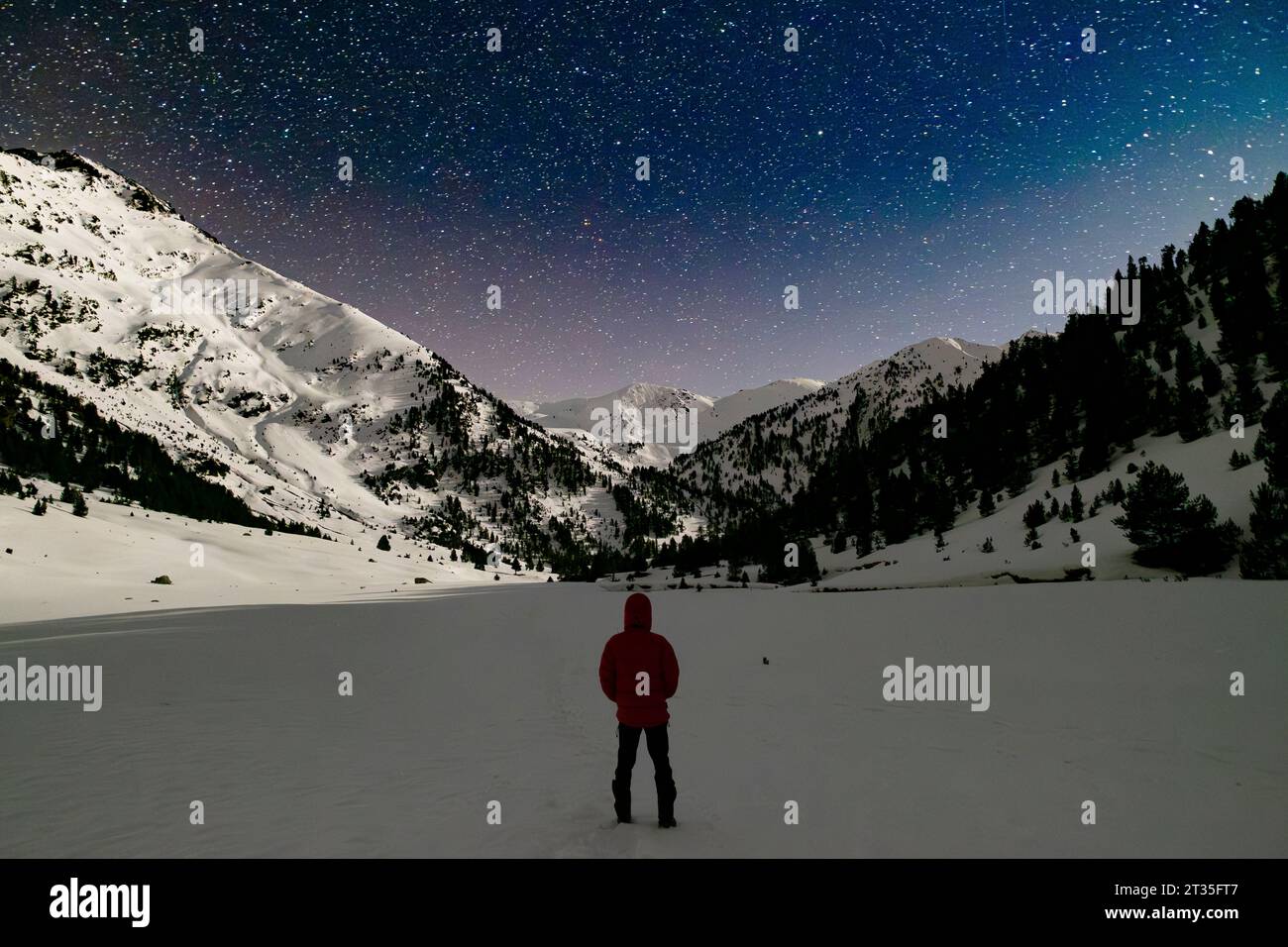 Escursionista che osserva le stelle in un paesaggio innevato di montagna nei Pirenei Foto Stock