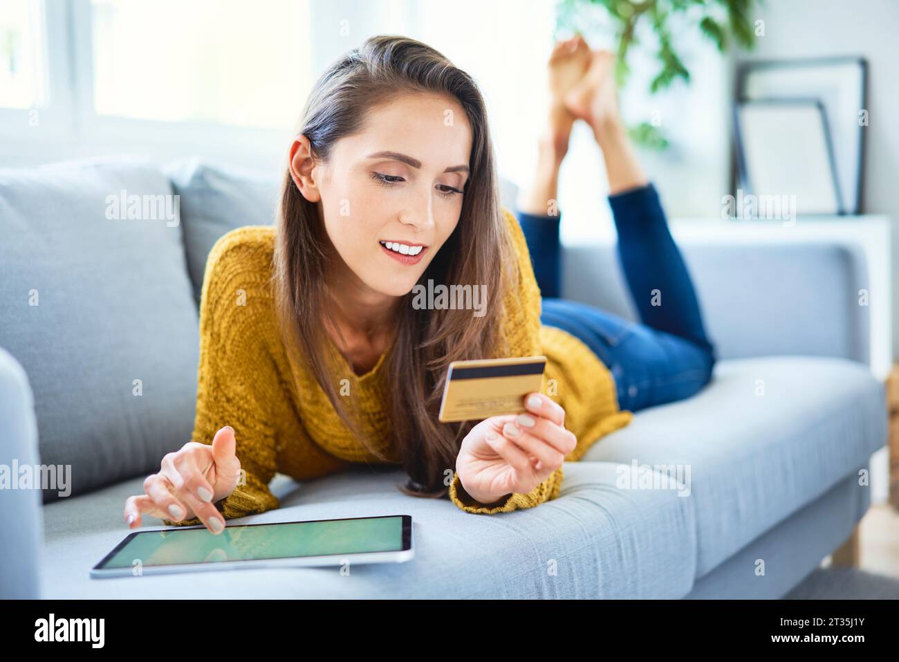 Bella donna sorridente che acquista online utilizzando tablet e carta di credito Foto Stock