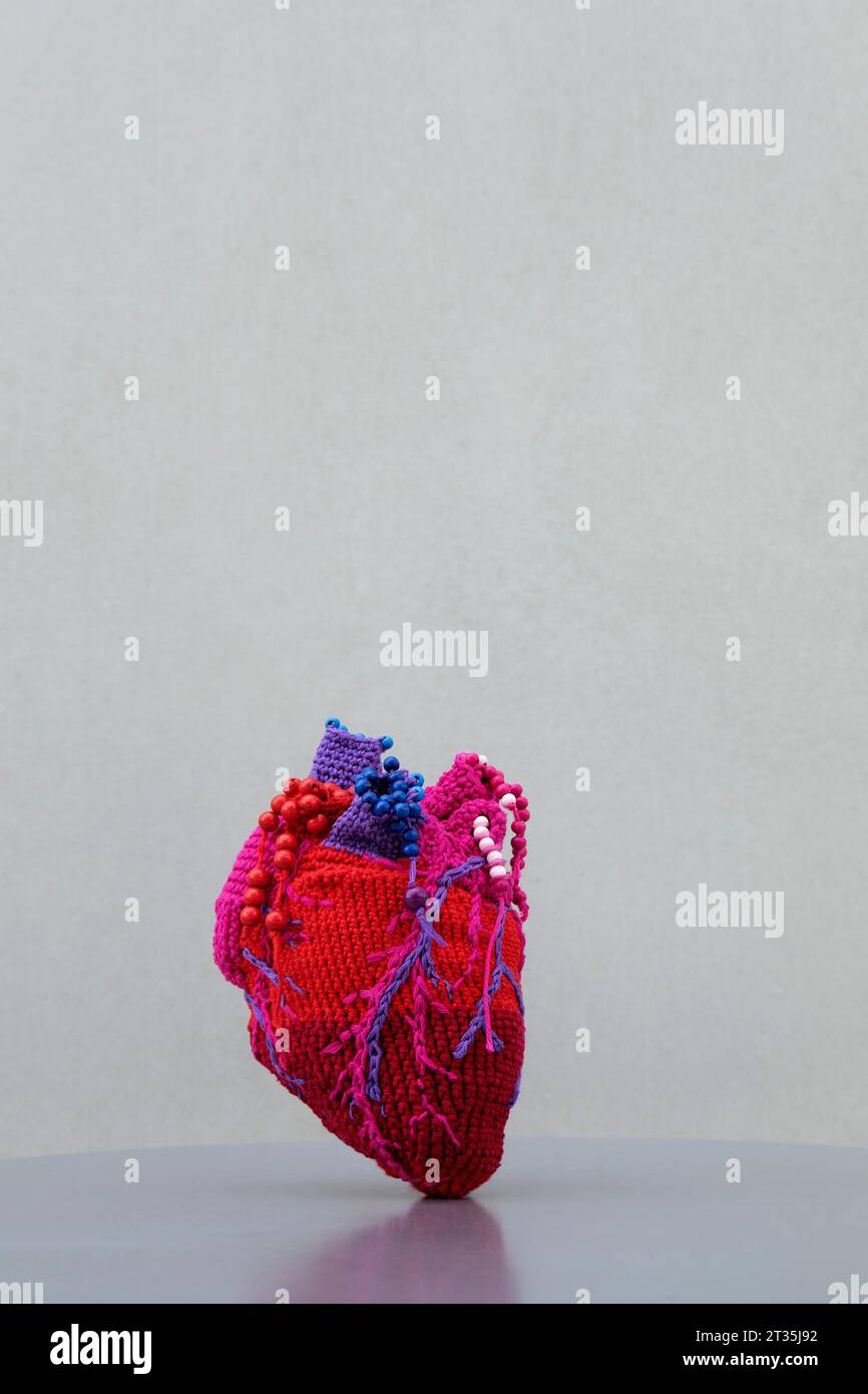 Cuore di lana rosso sul tavolo su sfondo grigio Foto Stock