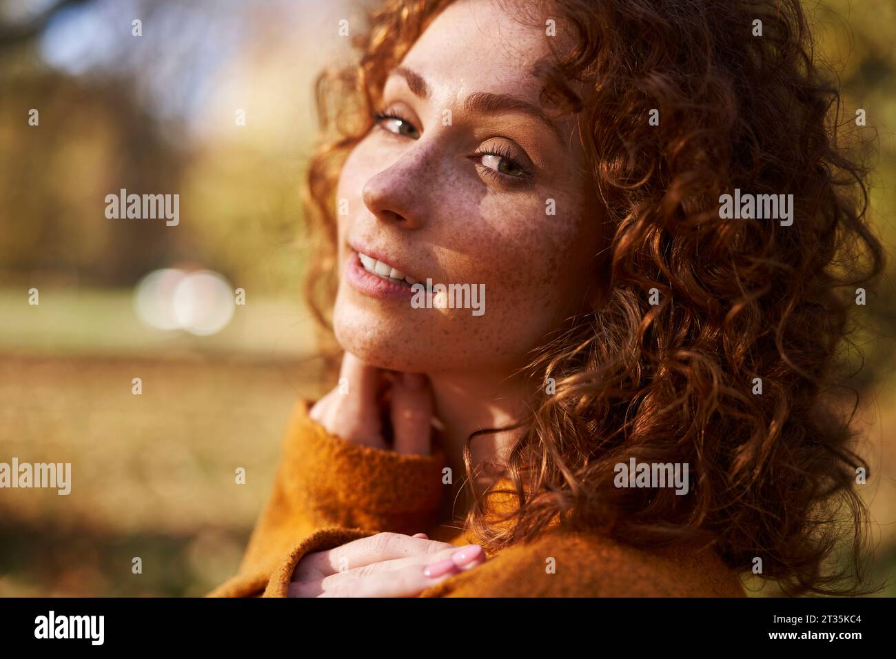 Giovane donna rossa sorridente al parco autunnale Foto Stock
