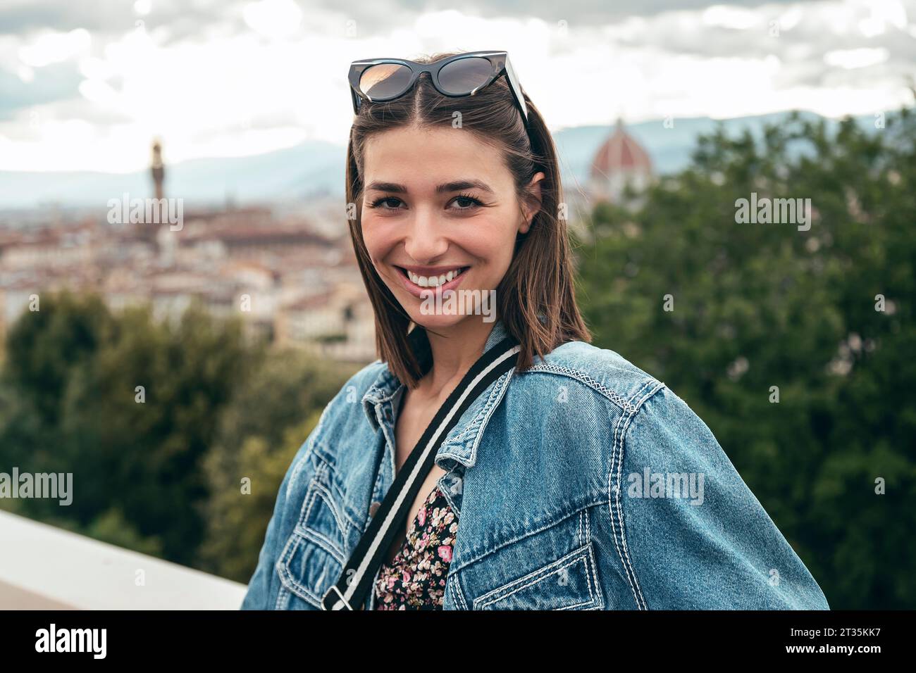 Donna sorridente in piedi sopra la città Foto Stock